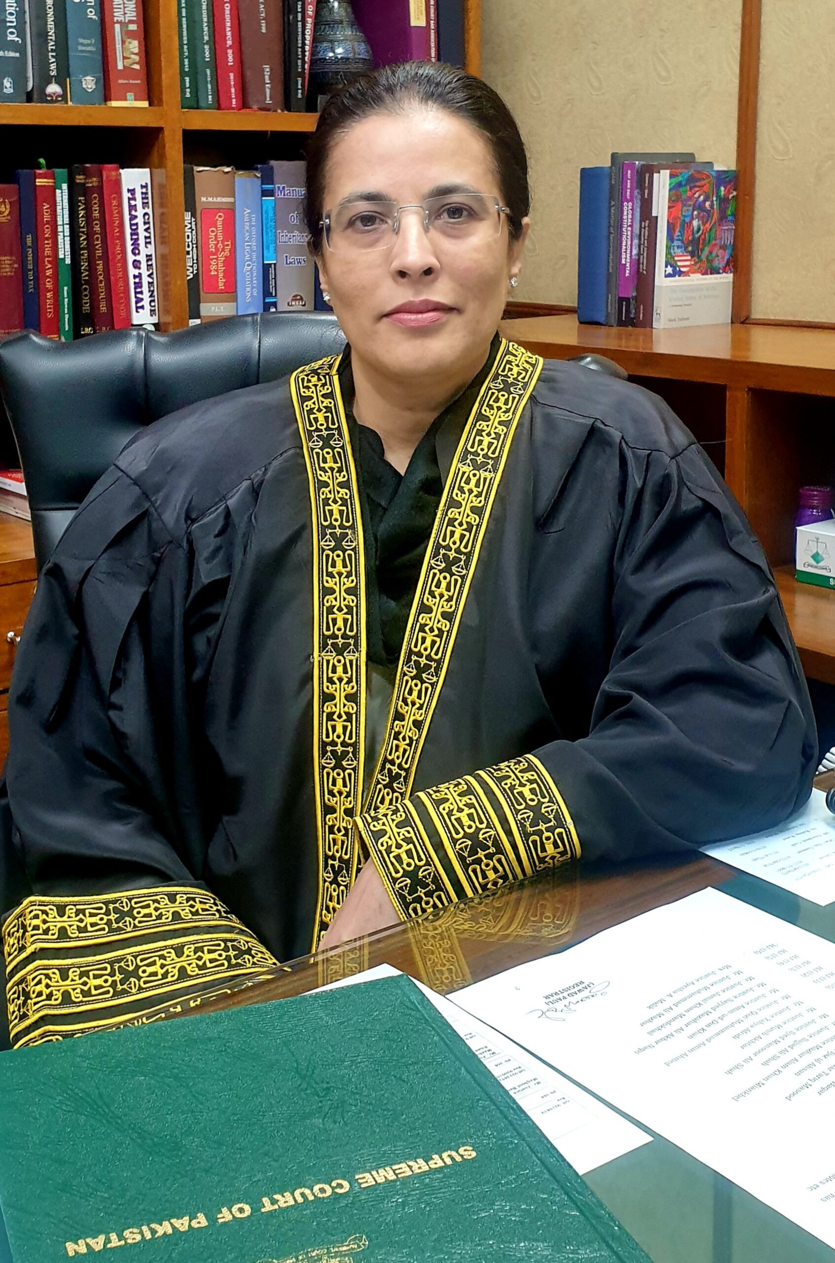 Mrs Justice Ayesha A. Malik at her desk, smiling into the camera
