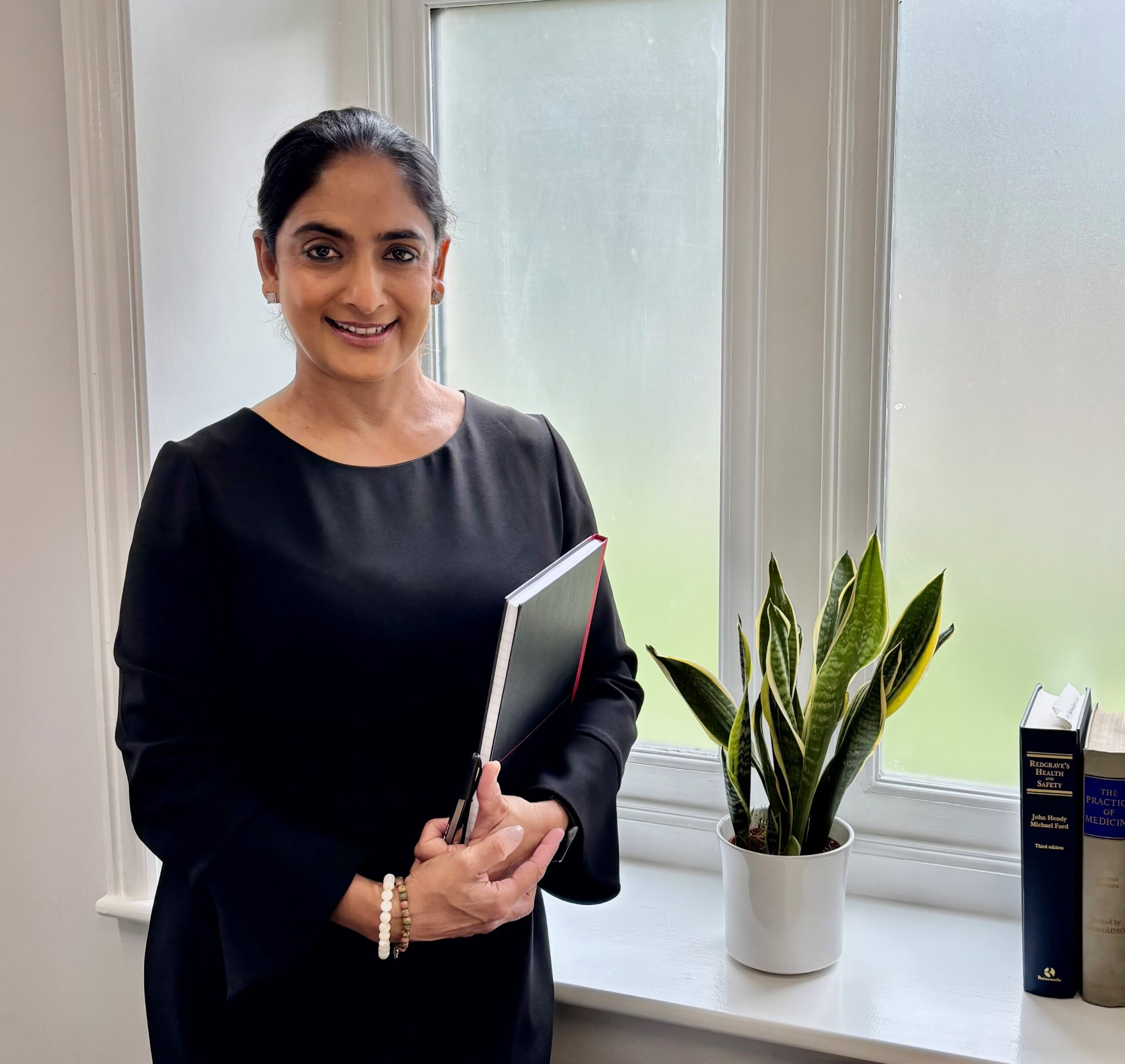 Nadia Persaud, in an office by the window, holding a book