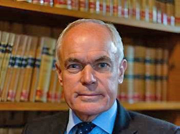 Lord Justice Dingemans, wearing suit and tie, with books behind him