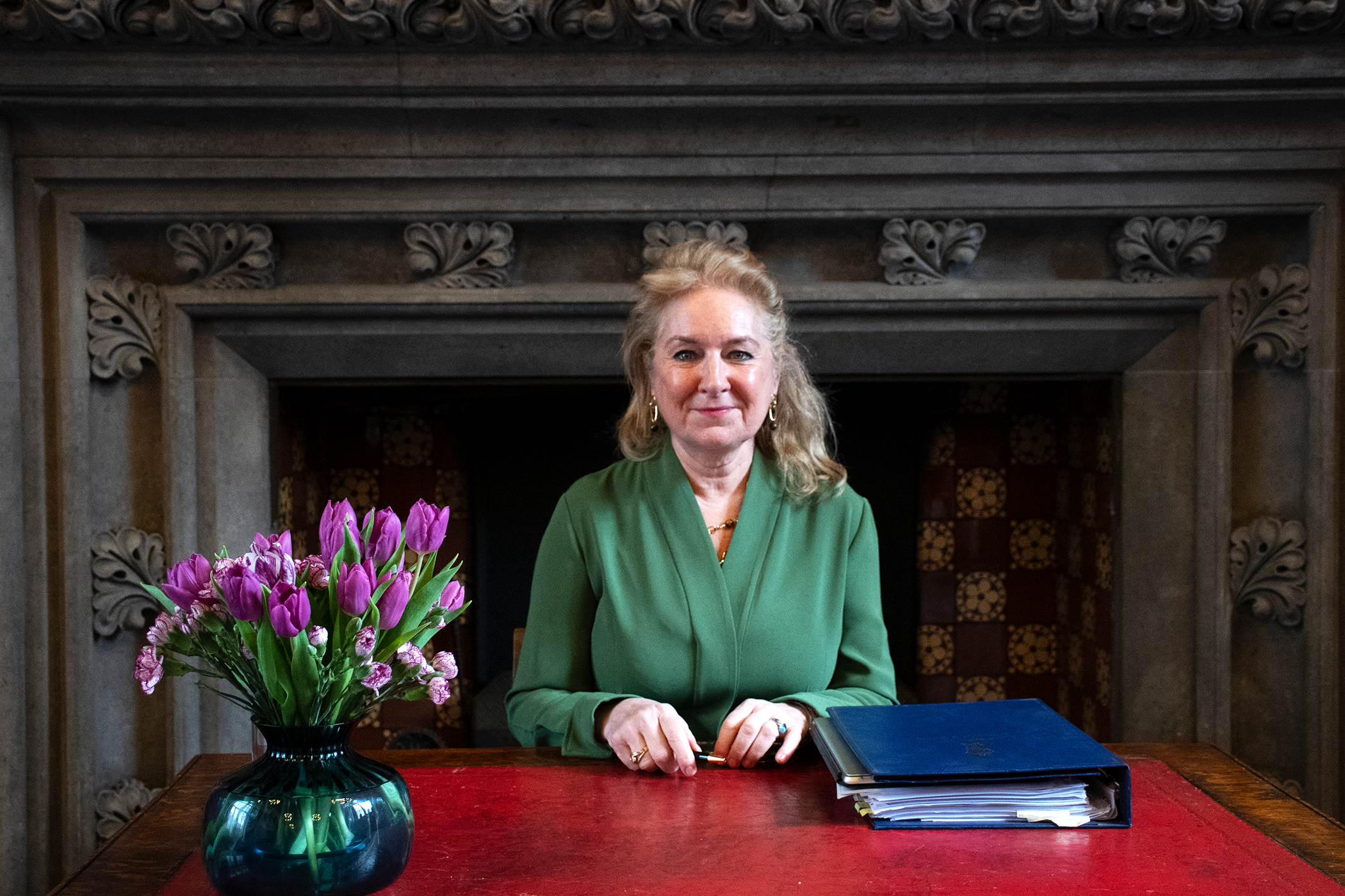 Lady Chief Justice sitting at desk, with folder and vase of flowers