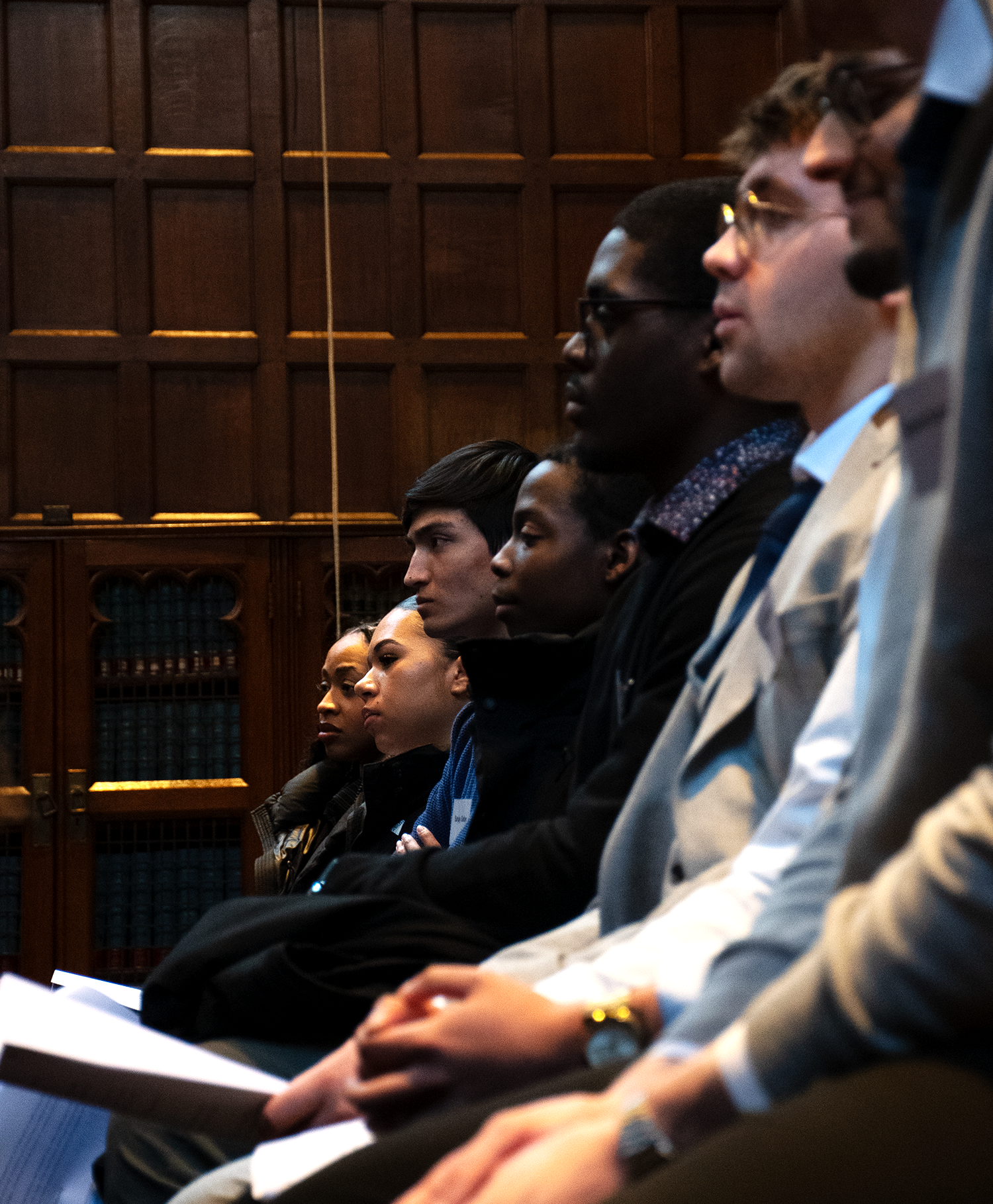 Students sat in a row of benches, listening to a talk