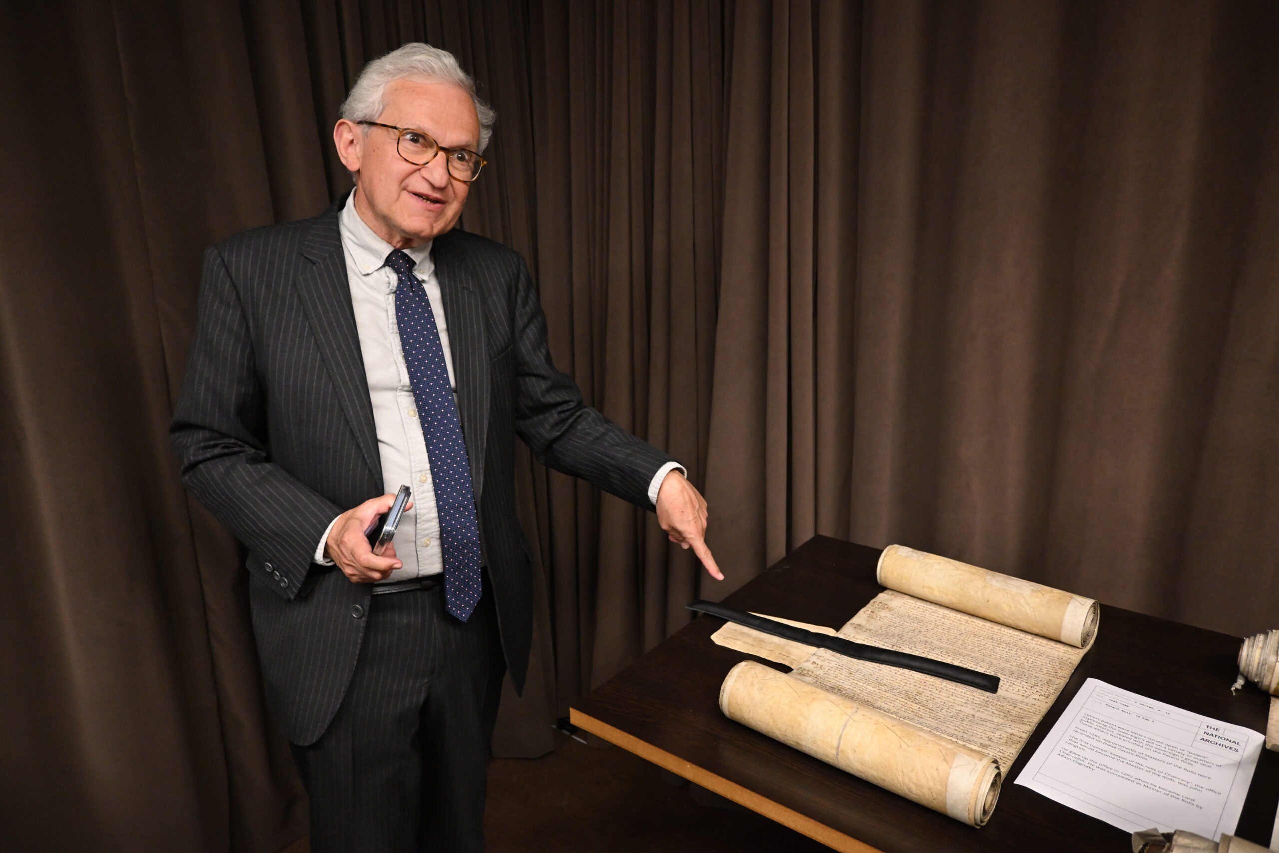Sir Geoffrey Vos, Master of the Rolls, pointing to a document on display at The National Archives